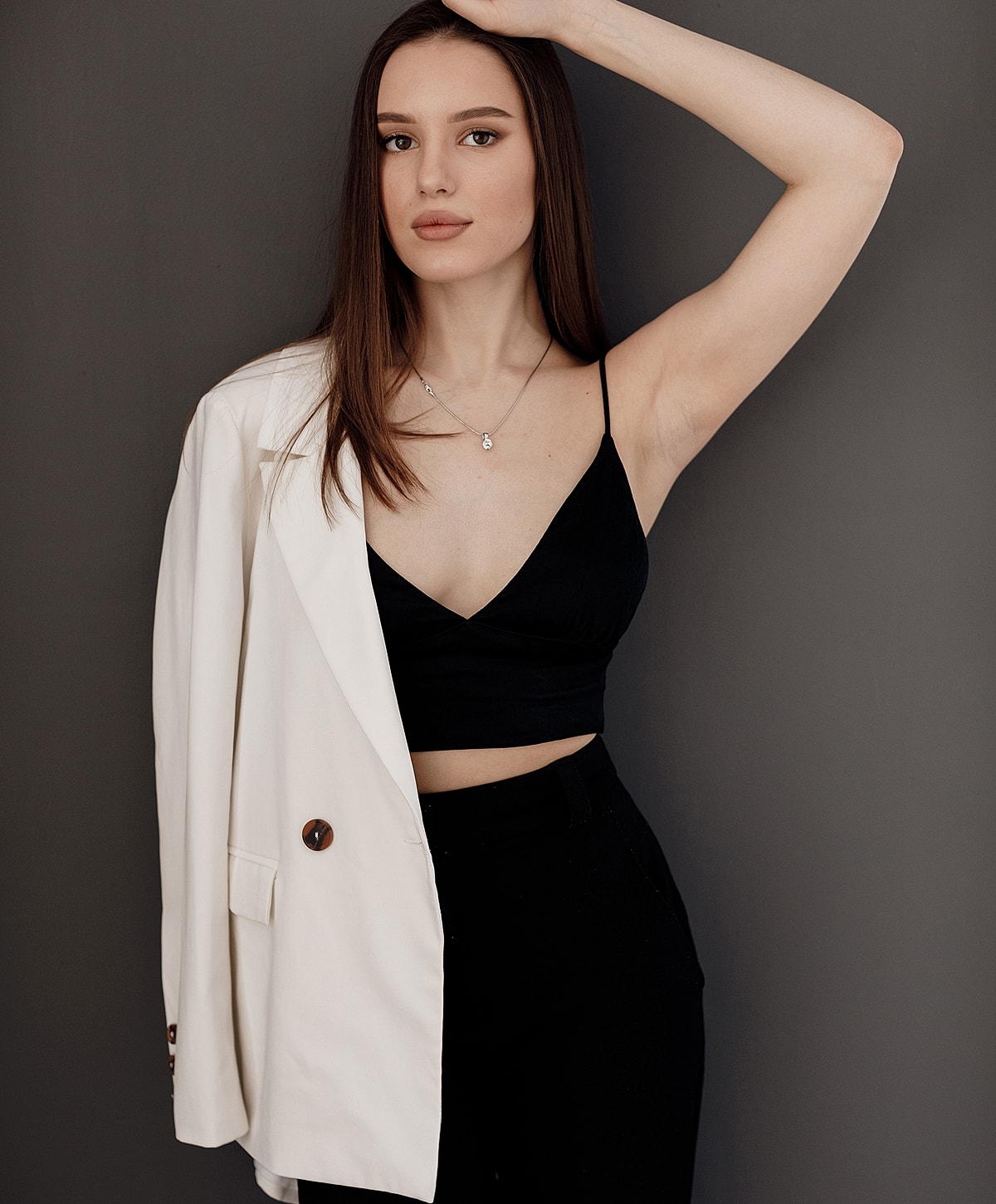 Woman in stylish outfit posing against gray background.