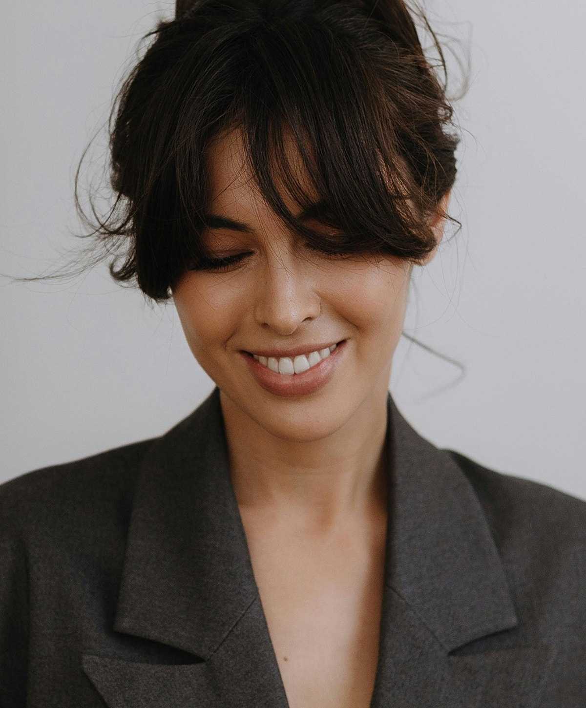 Smiling woman with tousled hair and blazer.