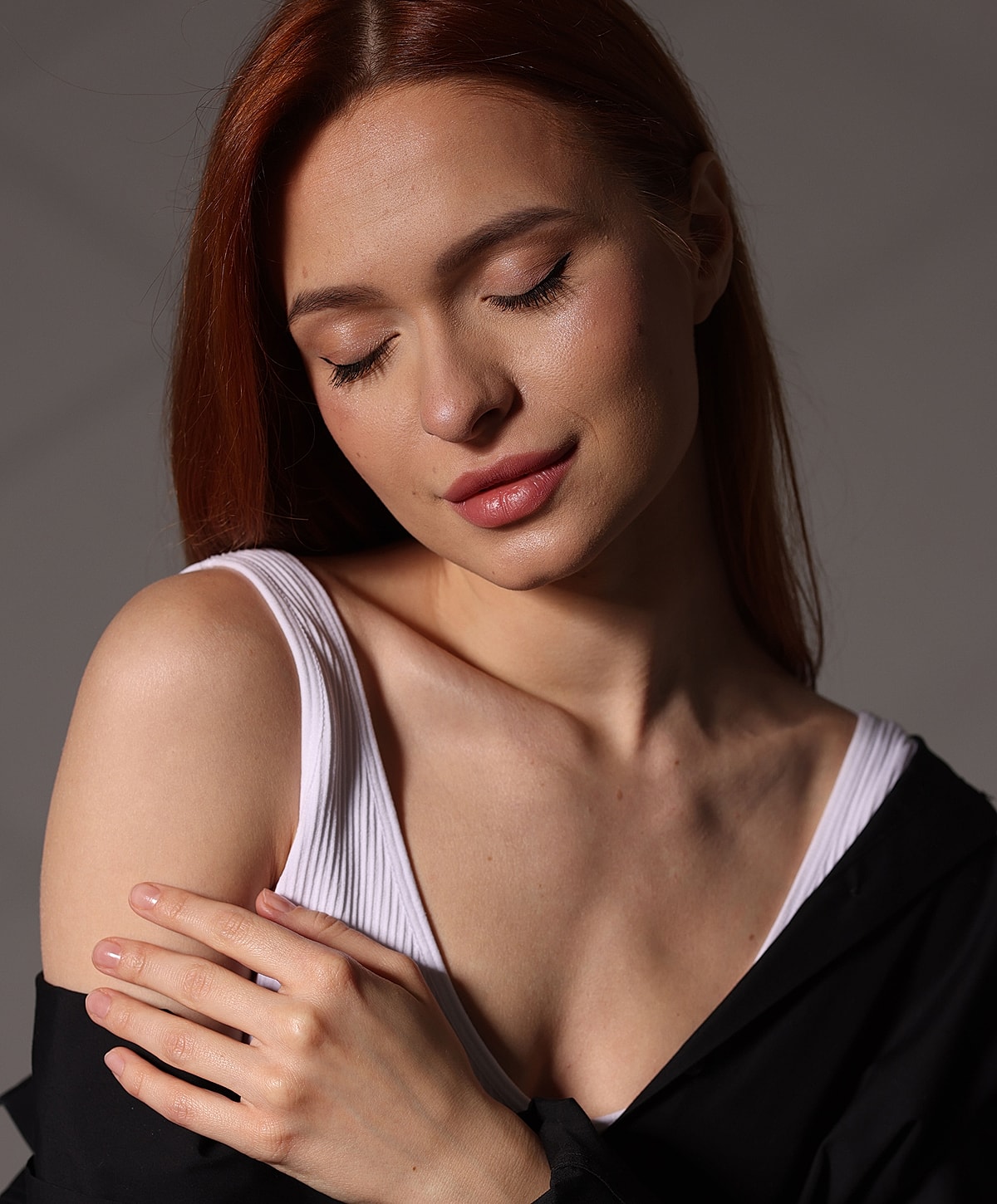 Woman with red hair, softly embracing herself.